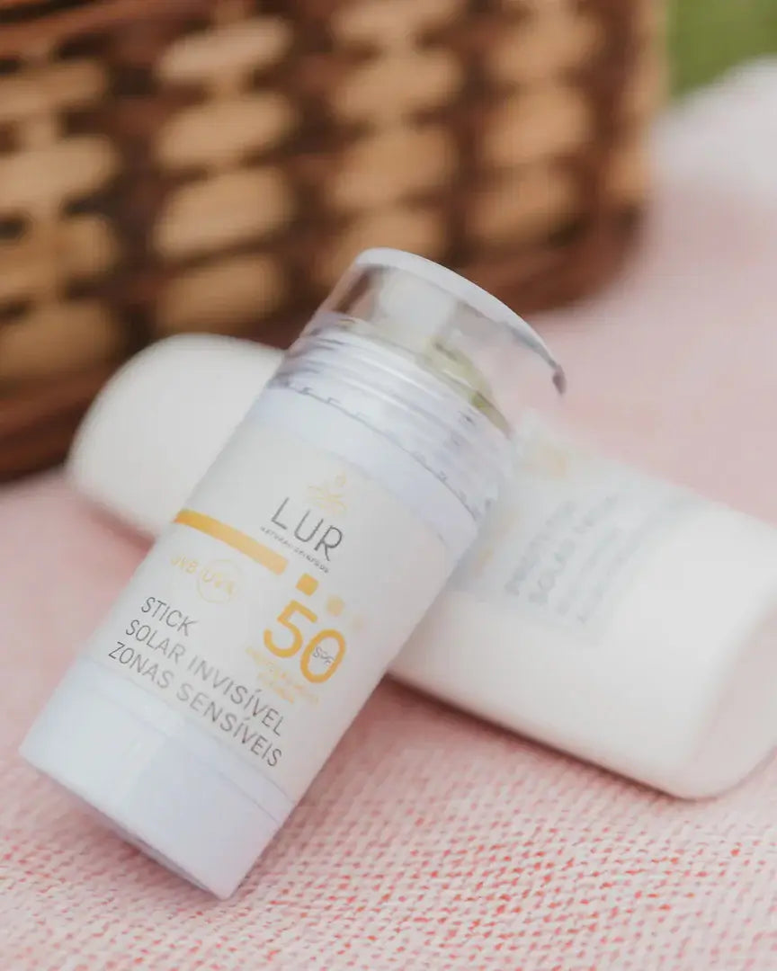 Sunscreen bottles with SPF 50 on a pink surface with a wicker basket in the background