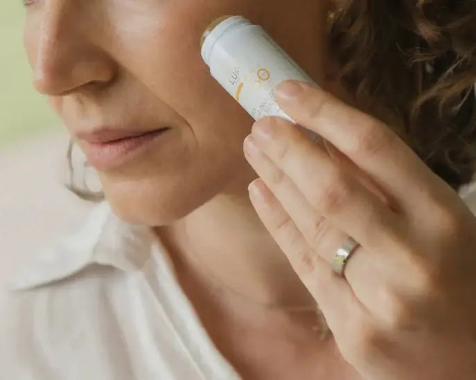 Woman applying sunscreen to her face with a focus on the product.